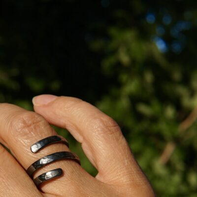 Bague torsade en argent oxydé portée au doigt, avec texture martelée