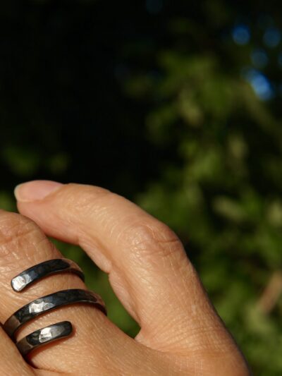 Bague torsade en argent oxydé portée au doigt, avec texture martelée