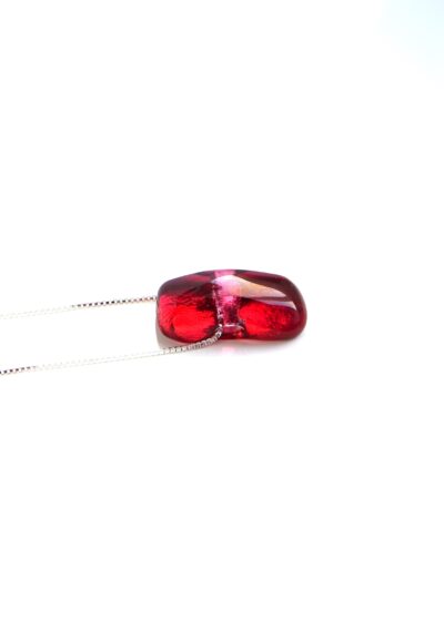 Pendentif en cristal de verre rouge framboise, légèrement arrondi et translucide, suspendu à une chaîne fine en argent